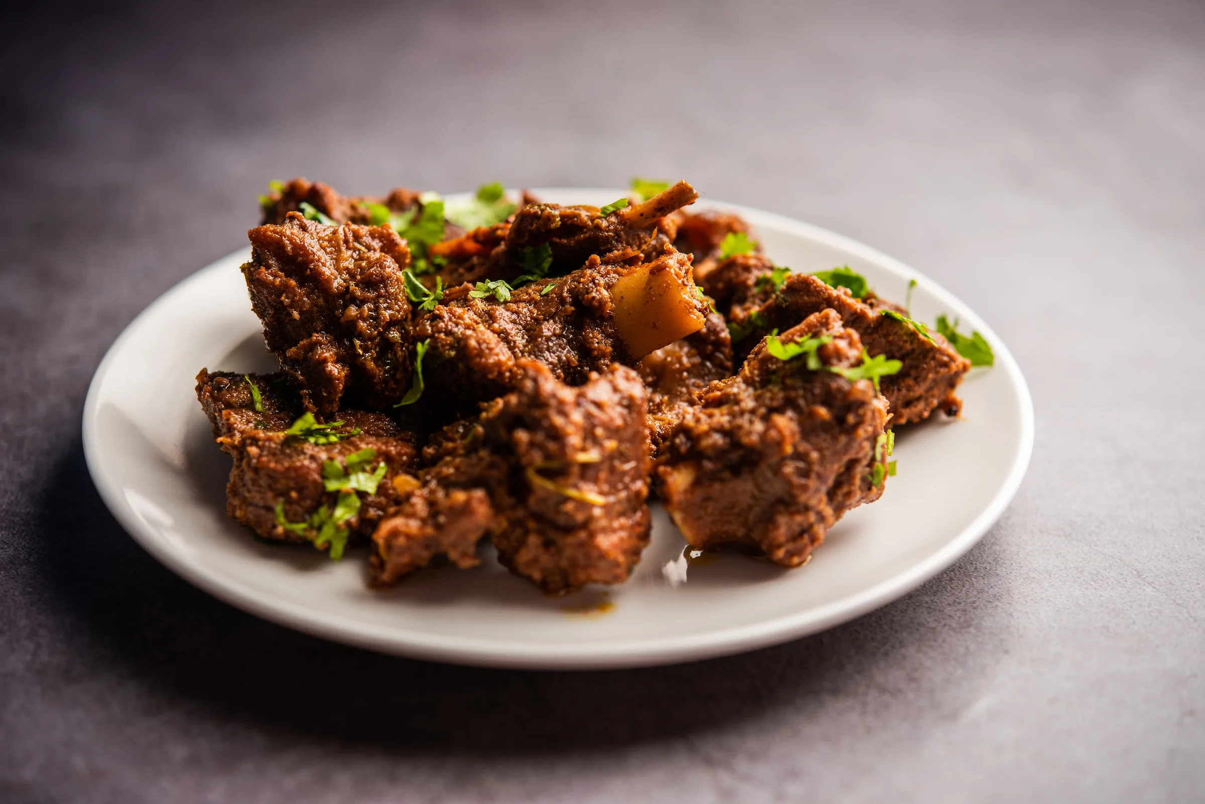A beautifully arranged plate of meat, complemented by a sprinkle of fresh parsley, showcasing a delicious culinary dish.